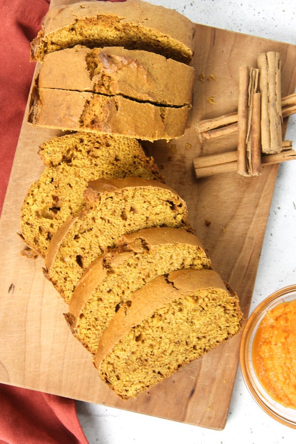 This Easy Pumpkin Bread is the perfect moist, quick bread! It's made with canned pumpkin, cinnamon, ginger and nutmeg! Pumpkin Bread overhead view on cutting board
