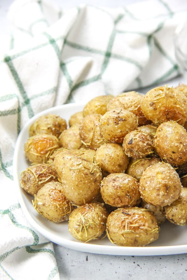 Roasted Rosemary Potatoes bakes up quick and easy! Creamy potatoes loaded with rosemary, for the best side dish! Roasted Rosemary Potatoes on white plate with green and white napkin