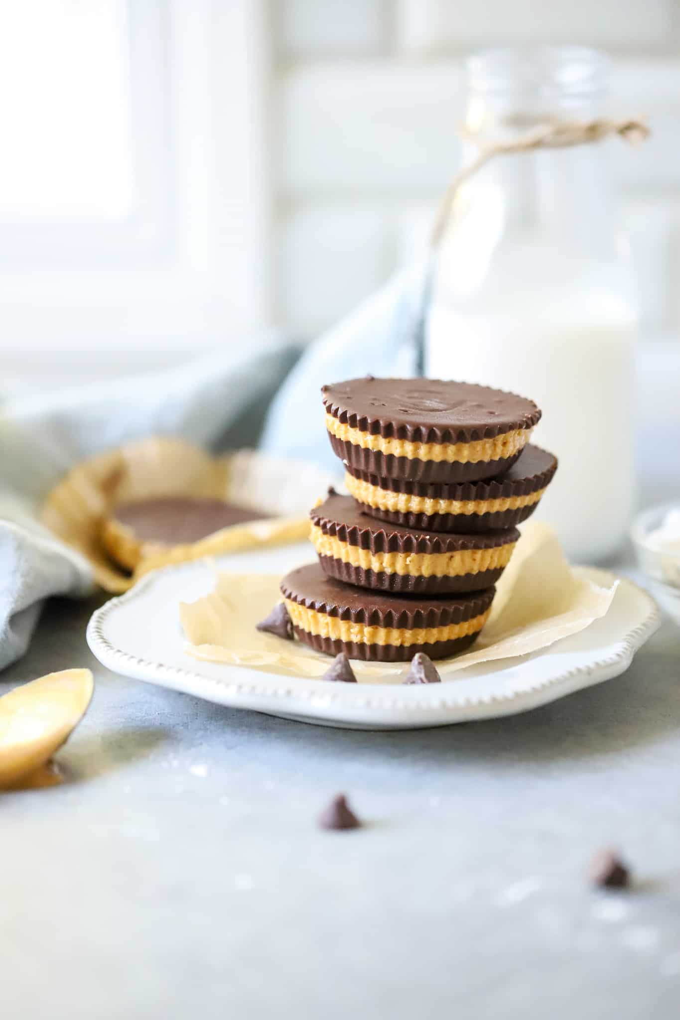 Easy Homemade Peanut Butter Cups! Layers of rich chocolate and creamy peanut butter, these are a fantastic treat! Perfect for freezing too! Homemade Peanut Butter Cups on white plate with glass of milk