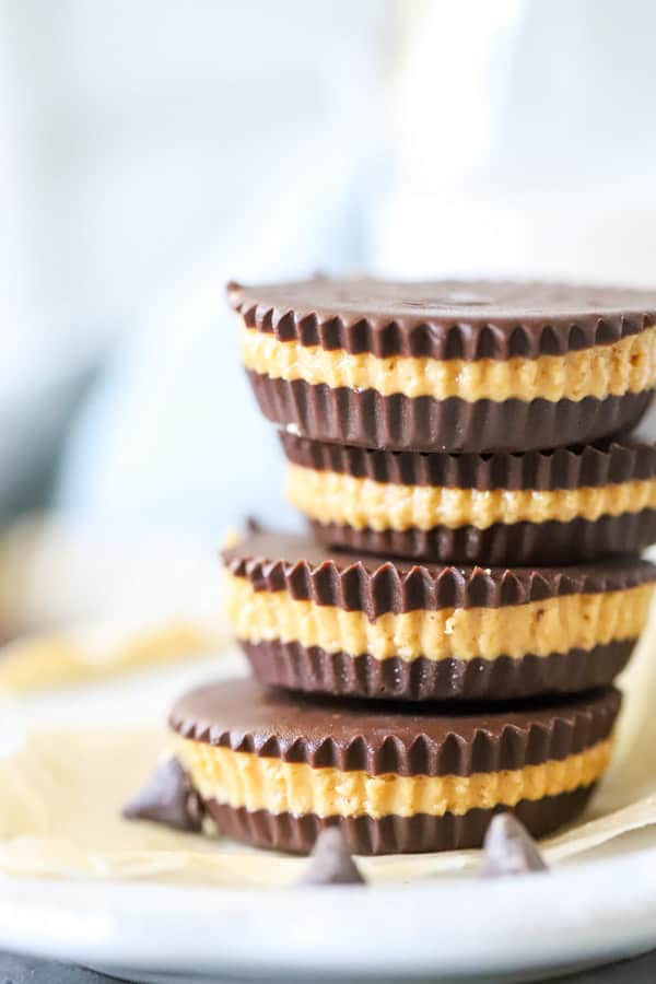Easy Homemade Peanut Butter Cups! Layers of rich chocolate and creamy peanut butter, these are a fantastic treat! Perfect for freezing too! Homemade Peanut Butter Cups stacked on white plate