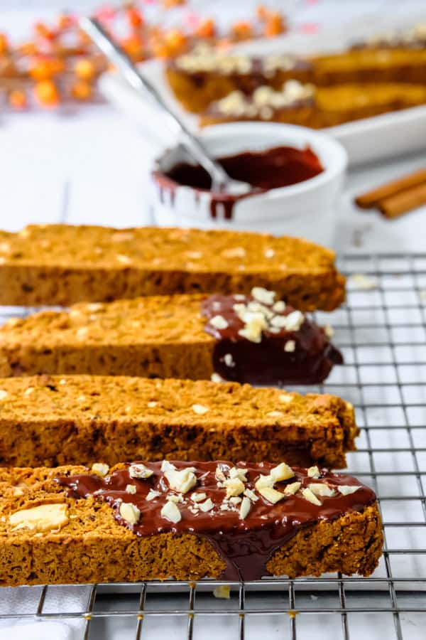 These delicious Homemade Pumpkin Biscotti is the perfect treat to go with your coffee or tea! Drizzled with chocolate and a sprinkle of nuts! Homemade Pumpkin Biscotti on wire rack