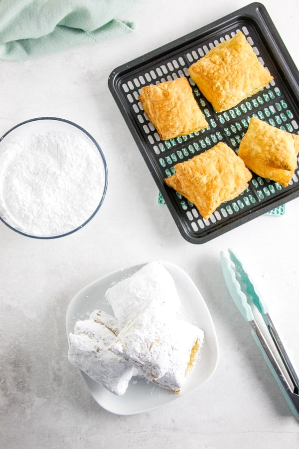 Easy 2 ingredient Air Fryer Beignets! Made with buttery puff pastry and coated with powdered sugar with no oil! Ready in 9 minutes! overhead view of Air Fryer Beignets.