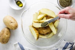 potatoes in glass bowl adding basil.