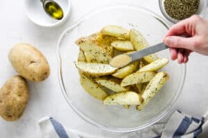 potatoes in glass bowl adding garlic powder.