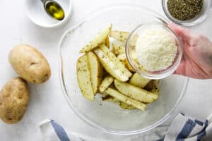 potatoes in glass bowl adding parmesan cheese.