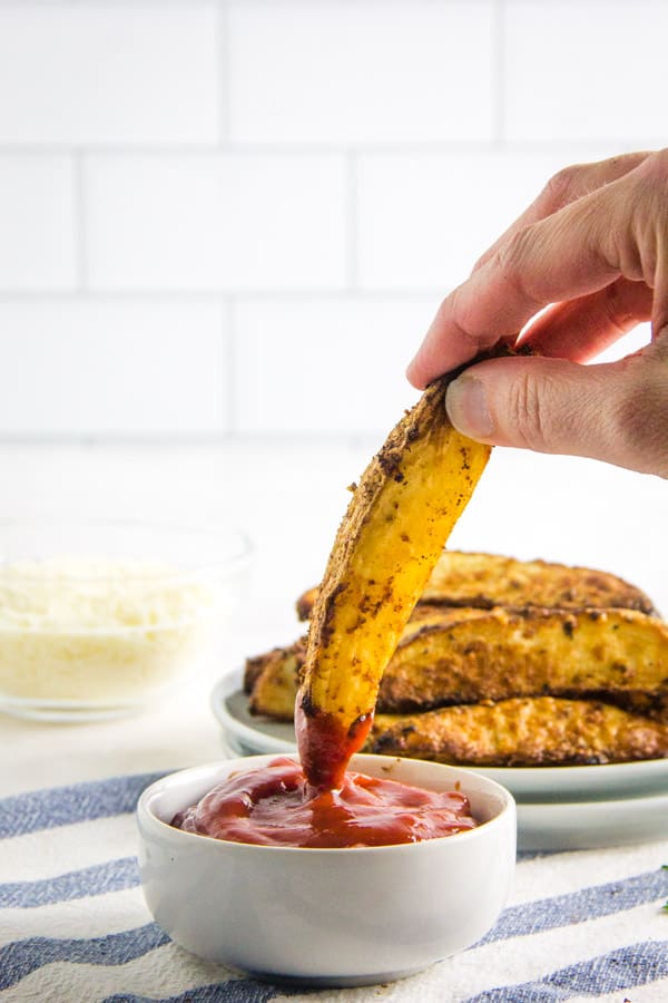 These easy to make Air Fryer Parmesan Potato Wedges cook up in just 20 minutes! Topped with flavors of basil, garlic and cheese! Air Fryer Parmesan Potato Wedges dipped in ketchup.