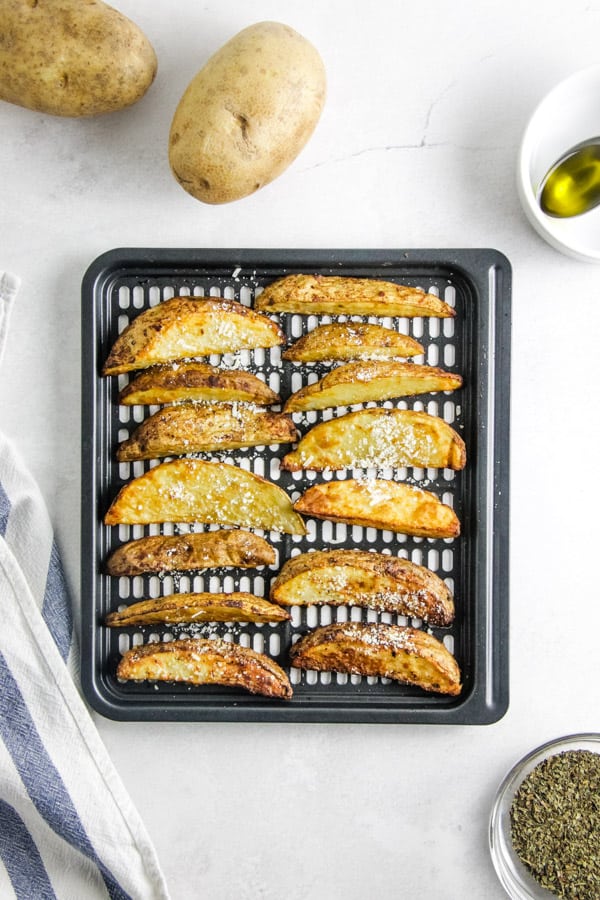 These easy to make Air Fryer Parmesan Potato Wedges cook up in just 20 minutes! Topped with flavors of basil, garlic and cheese! potato wedges on crisper tray.