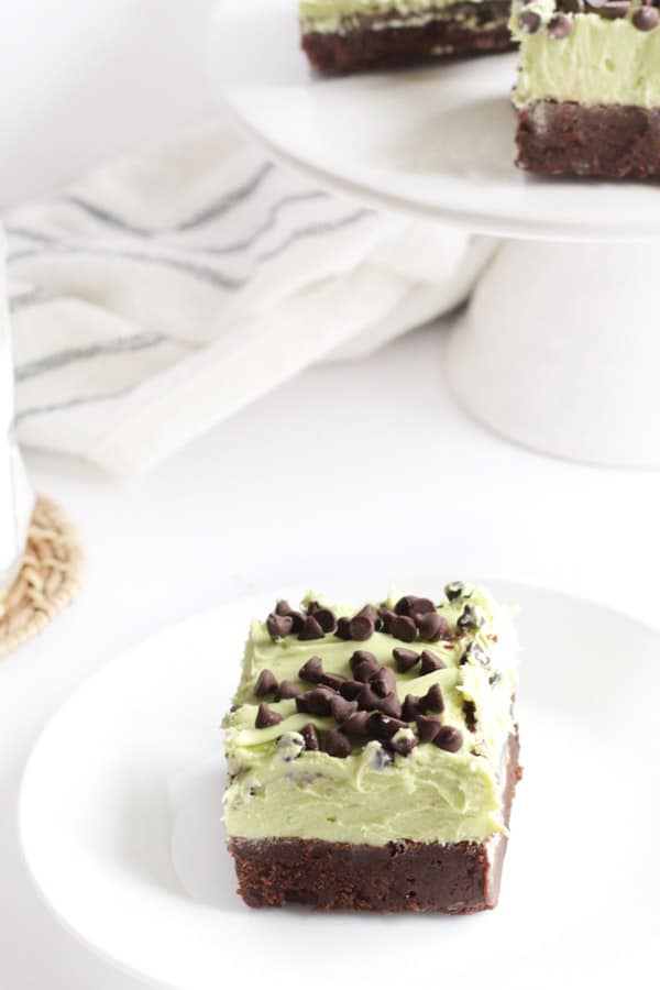 Mint Chocolate Chip Brownies are fudgy and decadent dessert. Topped with a semi-homemade frosting, with lots of mint flavor! Mint Chocolate Chip Brownies single slice on white plate.