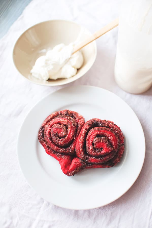 These Red Velvet Cinnamon Rolls are such a fun treat for breakfast or brunch! Made with a homemade dough and topped with a gooey frosting! Red Velvet Cinnamon Rolls on plate with no frosting