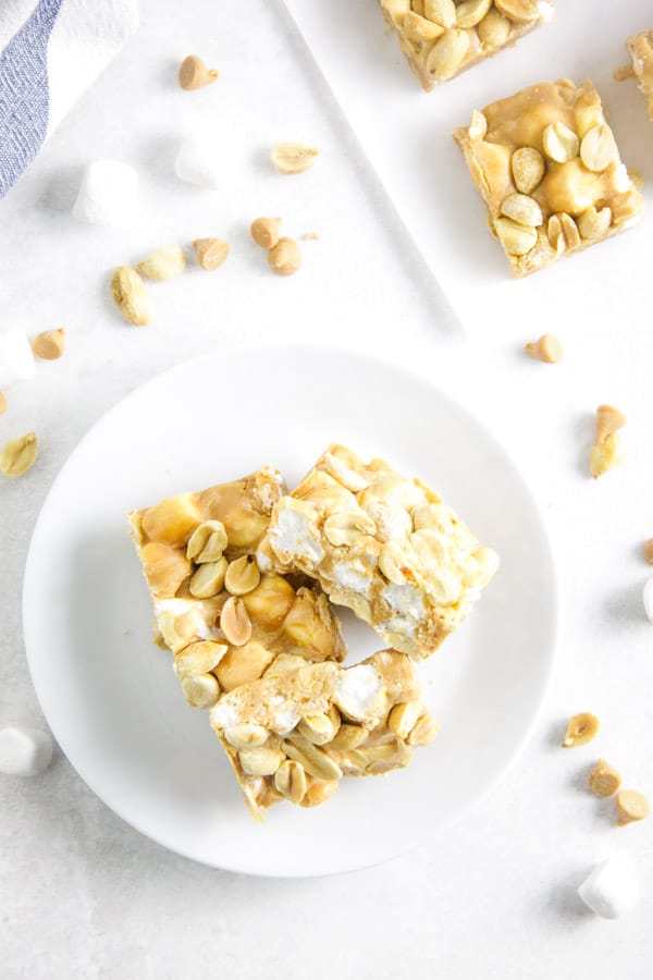 Salted Nut Roll Bars are a candy classic made into a delicious ooey gooey bar! Filled with peanut butter and marshmallows, the whole family would enjoy it! bars on white plate