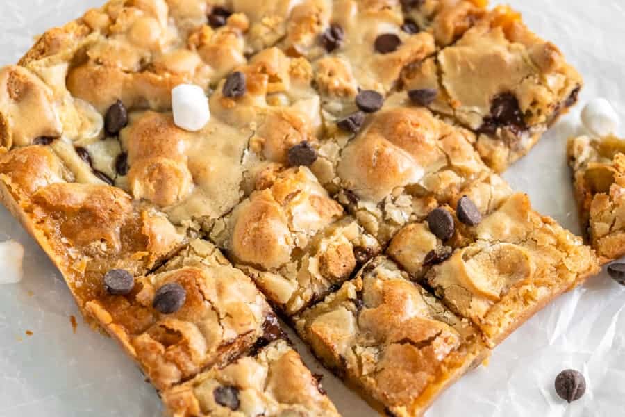Easy S'mores Blondies are full of your favorite summertime flavors wrapped up in one bar! Perfect all year round! S'mores Blondies cut into pieces on parchment paper.
