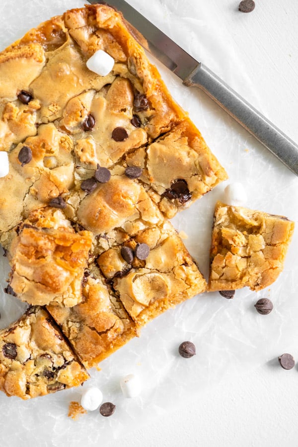 Easy S'mores Blondies are full of your favorite summertime flavors wrapped up in one bar! Perfect all year round! S'mores Blondies on white parchment paper with knife.
