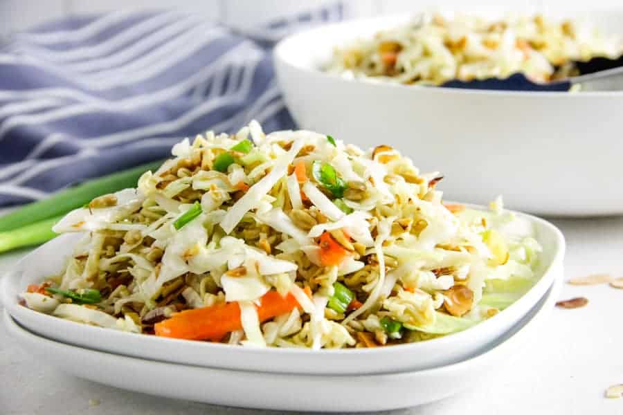 This easy Ramen Salad is a delicious side dish full of toasted almonds, sunflower seeds and topped with a tasty vinegar dressing! Easy Ramen Salad on white plate.