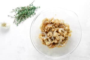 uncooked shrimp in glass bowl mixed in bowl with seasonings.