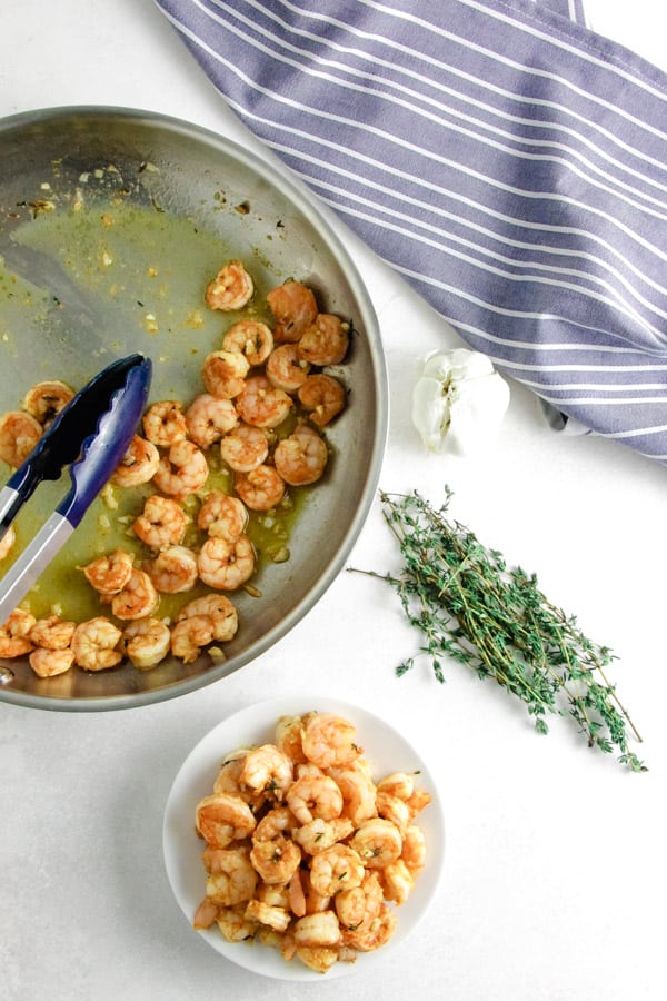Quick and easy Spicy Garlic Thyme Shrimp! Loads of flavor and made with just 6 ingredients! Spicy Garlic Thyme Shrimp in pan and on white plate.