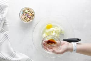 adding vanilla to glass bowl.