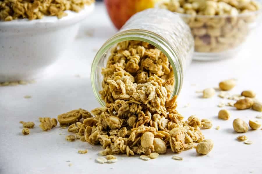 This easy Peanut Butter Granola snack is so delicious, you will be making it over and over again! Packed with peanut butter flavor! granola spilling out of mason jar.