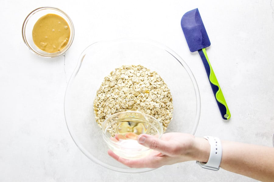 pouring canola oil in glass bowl with oats.