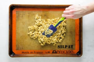 spreading out granola on sheet pan.