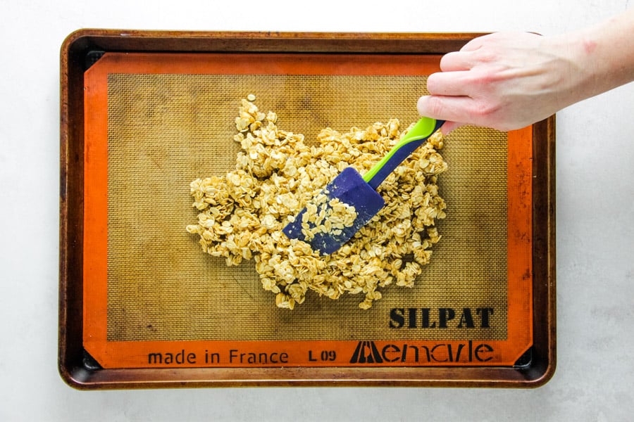 spreading out granola on sheet pan.