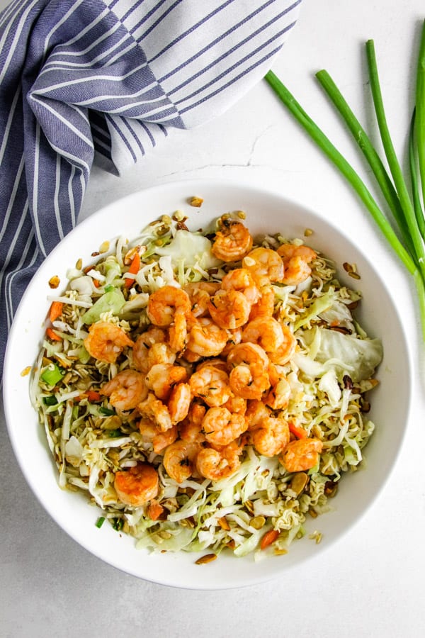 Delicious, but simple Shrimp Ramen Salad! With spicy shrimp, toasted almonds, sunflower seeds and a shrimp flavored dressing! salad and shrimp in bowl.