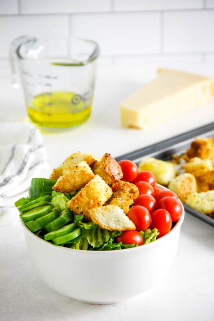 These Air Fryer Croutons are the perfect addition to salads or soups! Made with breads, spices and freshly grated Parmesan cheese! croutons topped on salad in white bowl.