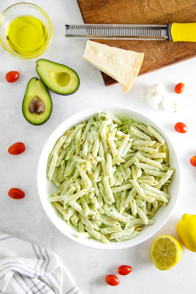 This Creamy Avocado Pasta is silky, fresh, and easy to prep! Use a ripe avocado, fresh tomatoes top it over your favorite pasta noodle! Ready in less than 30 minutes, make for an easy week night meal! avocado pasta in large white bowl.