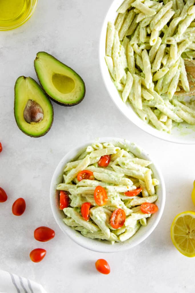 This Creamy Avocado Pasta is silky, fresh, and easy to prep! Use a ripe avocado, fresh tomatoes top it over your favorite pasta noodle! Ready in less than 30 minutes, make for an easy week night meal! overhead view of creamy avocado pasta in bowl.