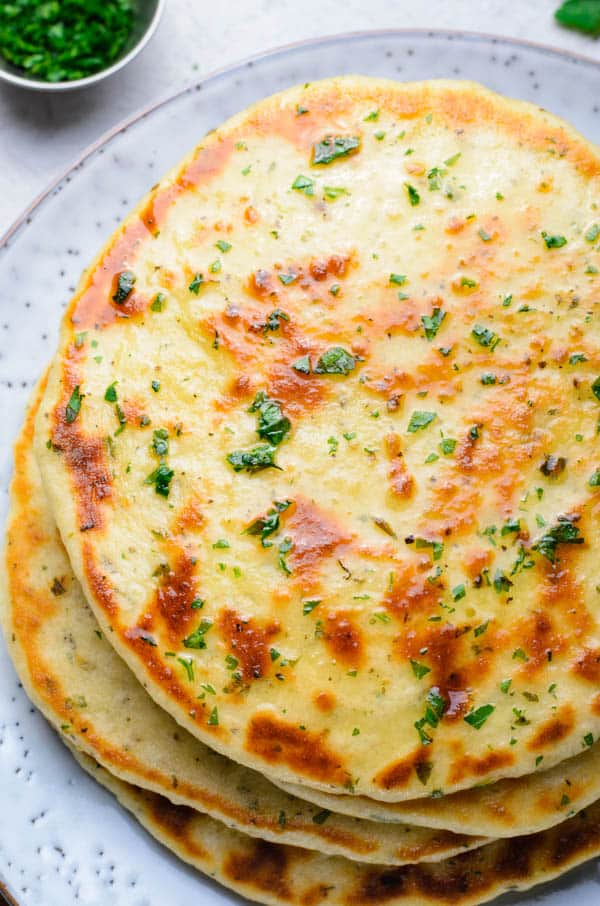 Easy Homemade Flatbread will be the only flatbread you will ever need! Learn how to make these soft, spongy, filled with herbs bread! flatbread stacked on plate.