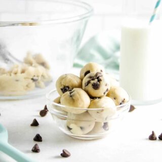 cookie dough bites in bowl with glass of milk.