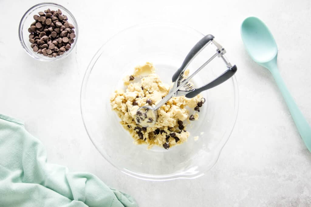 These easy no bake Cookie Dough Bites are made with a few simple ingredients! They are rolled into balls, eaten with a spoon or can be frozen! cookie scoop in glass bowl.