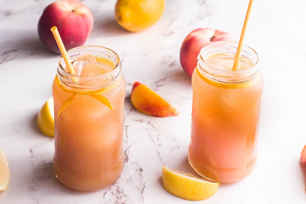 This simple, refreshing Peach Black Tea Lemonade has the perfect blend of flavors and just a touch of sweetness! Perfect for hot summer days! Peach Black Tea Lemonade in jar with peaches and lemons.