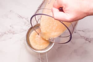 straining lemonade into cup.