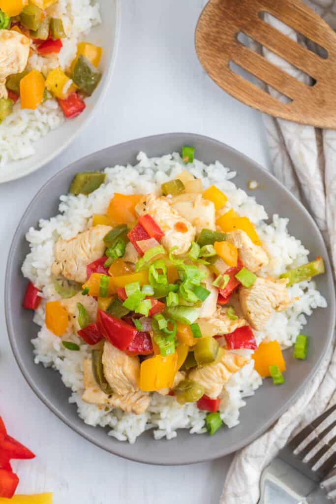 Italian Dressing Chicken Stir Fry takes very little time to make but is popping with lots of color and flavors that won't disappoint. stir fry cooked on gray plate over rice.
