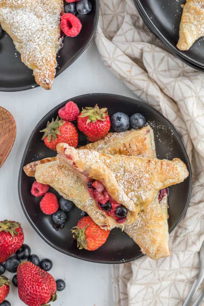Mixed Berry Turnovers can brighten up your breakfast or your dessert. They are ready in less than half an hour, too! Use any kind of fresh berry you want! cut turnover on black plate.