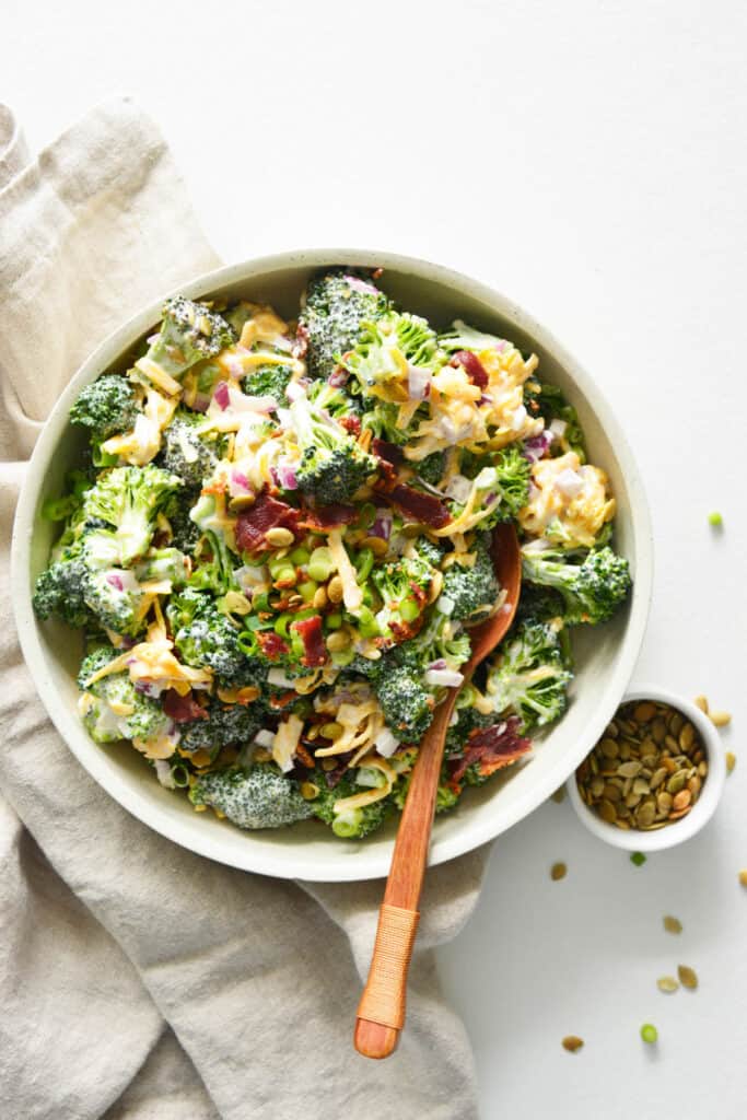 This Easy Broccoli Salad is made with bacon, cheddar cheese and a creamy mayonnaise sauce! Easy Broccoli Salad in bowl topped with bacon.