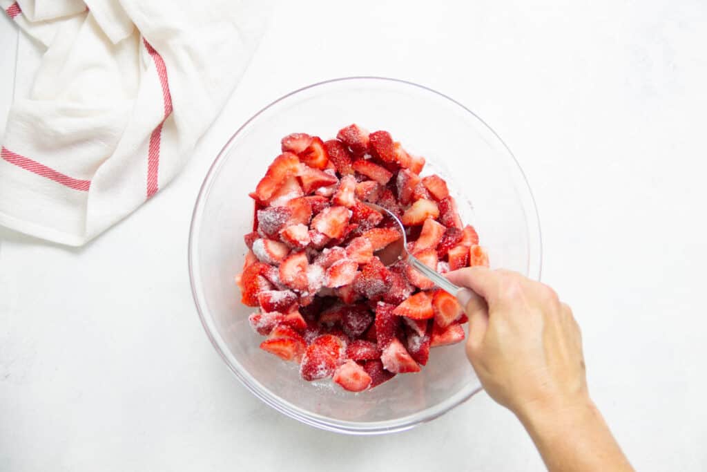 stirring sugar and strawberries together.