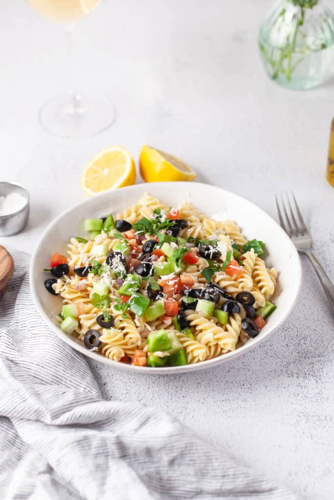Easy Greek Pasta Salad served cold with a homemade vinaigrette. With fresh vegetables topped with feta cheese! Greek Pasta Salad topped with cheese.