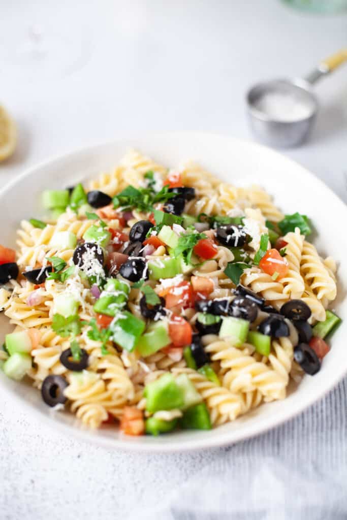 Easy Greek Pasta Salad served cold with a homemade vinaigrette. With fresh vegetables topped with feta cheese! Greek Pasta Salad topped with cheese and cilantro.