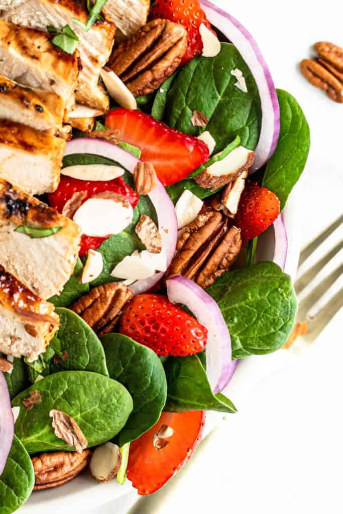 This easy Strawberry Chicken Spinach Salad is a delicious, complete meal! With marinated chicken, strawberries and a homemade vinaigrette! Strawberry Chicken Spinach Salad topped with strawberries.