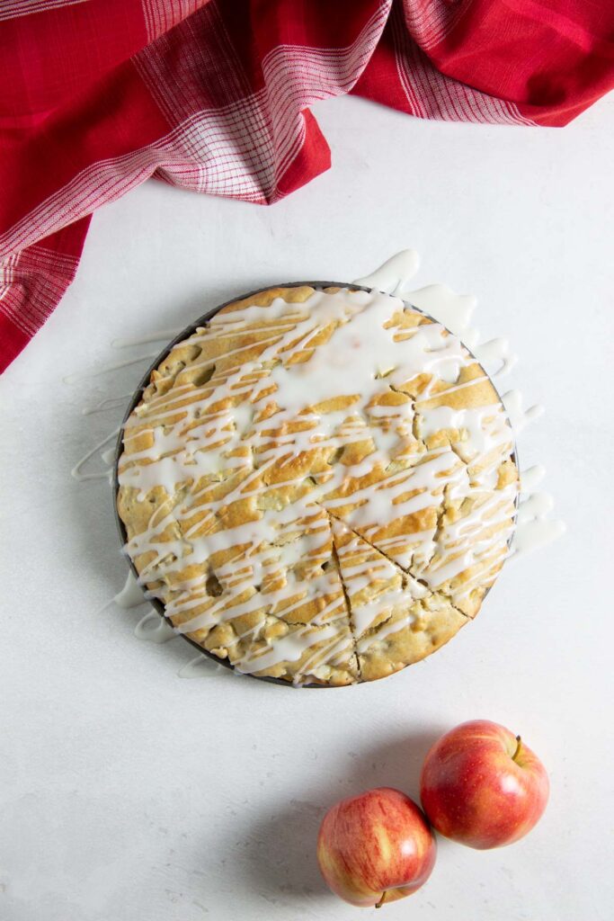 Easy Apple Cake! Made with just a few pantry staples and fresh apples! With a hint of cinnamon, this tasty dessert will become a favorite! overhead view of apple cake drizzled with icing.