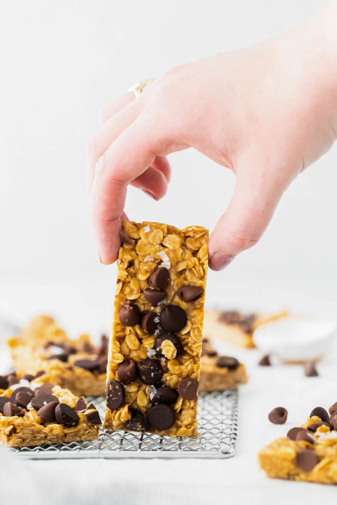 Chewy Oatmeal Granola Bars are made in just about 10 minutes! Filled with peanut butter, oats, honey, and any kind of chocolate chip! holding Chewy Oatmeal Granola Bars in hand.