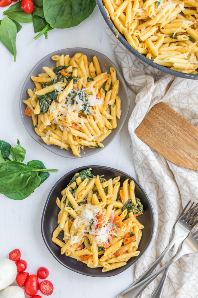 Creamy Tomato Spinach Pasta is what's for dinner tonight! It's full of fresh flavors, like tomato and spinach, and ready in minutes. Creamy Tomato Spinach Pasta on plates.