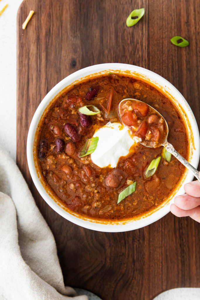 Easy Slow Cooker Chili with homemade seasoning and robust flavor! Packed with protein and perfect for a weeknight dinner! Slow Cooker Chili held in spoon.