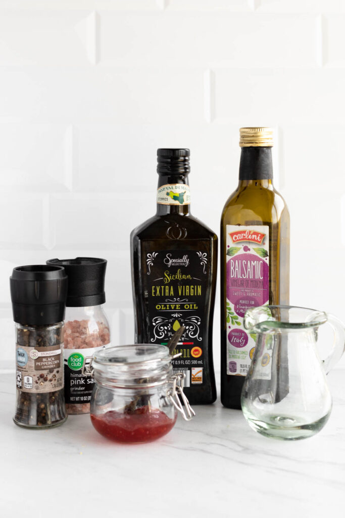 Easy homemade Strawberry Balsamic Vinaigrette! This easy dressing goes perfectly on any salad and it's customizable with any fruit jam! Strawberry Balsamic Vinaigrette ingredients on white background.
