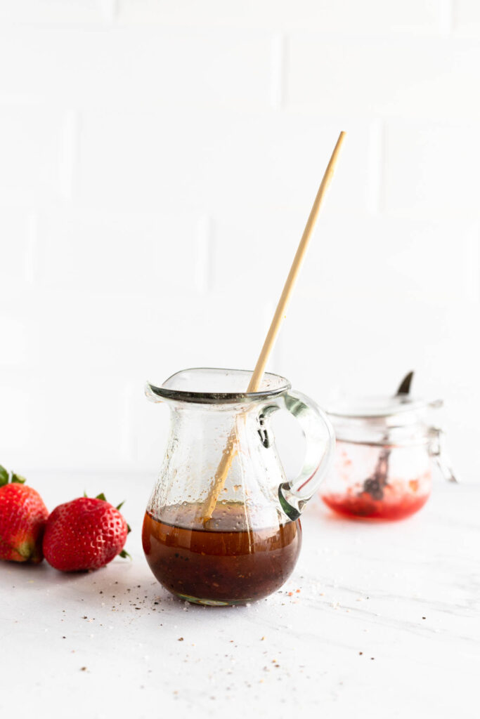 Easy homemade Strawberry Balsamic Vinaigrette! This easy dressing goes perfectly on any salad and it's customizable with any fruit jam! dressing mixing in glass pitcher.