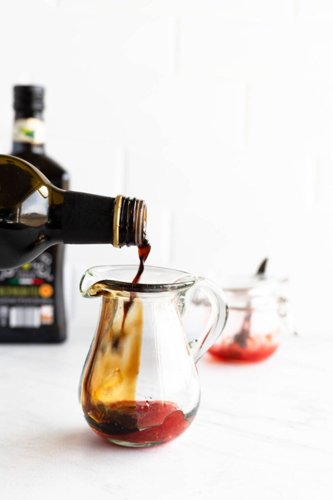 Easy homemade Strawberry Balsamic Vinaigrette! This easy dressing goes perfectly on any salad and it's customizable with any fruit jam! adding balsamic to glass pitcher.