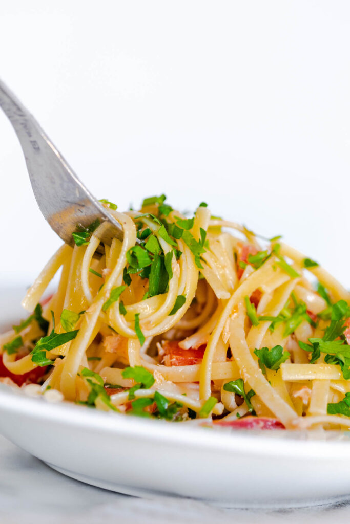 This easy Tuna Pasta With Tomatoes is perfect for a quick meal! With fresh tomatoes and parsley, this pasta can easily be modified! Tuna Pasta with Tomato in white bowl with fork.
