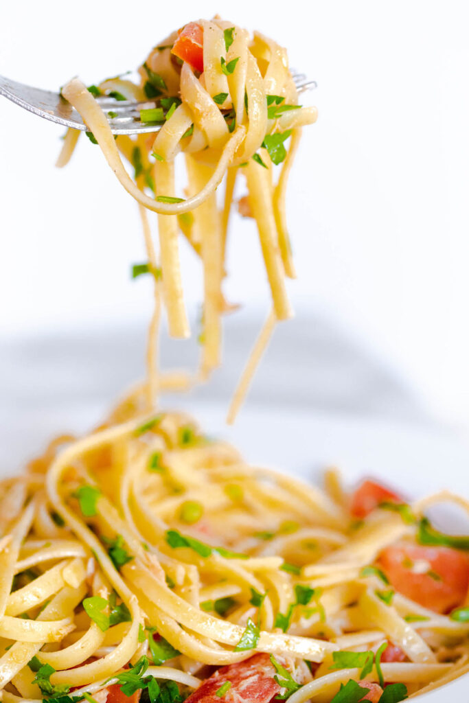 This easy Tuna Pasta With Tomatoes is perfect for a quick meal! With fresh tomatoes and parsley, this pasta can easily be modified! Tuna Pasta with Tomato on fork.