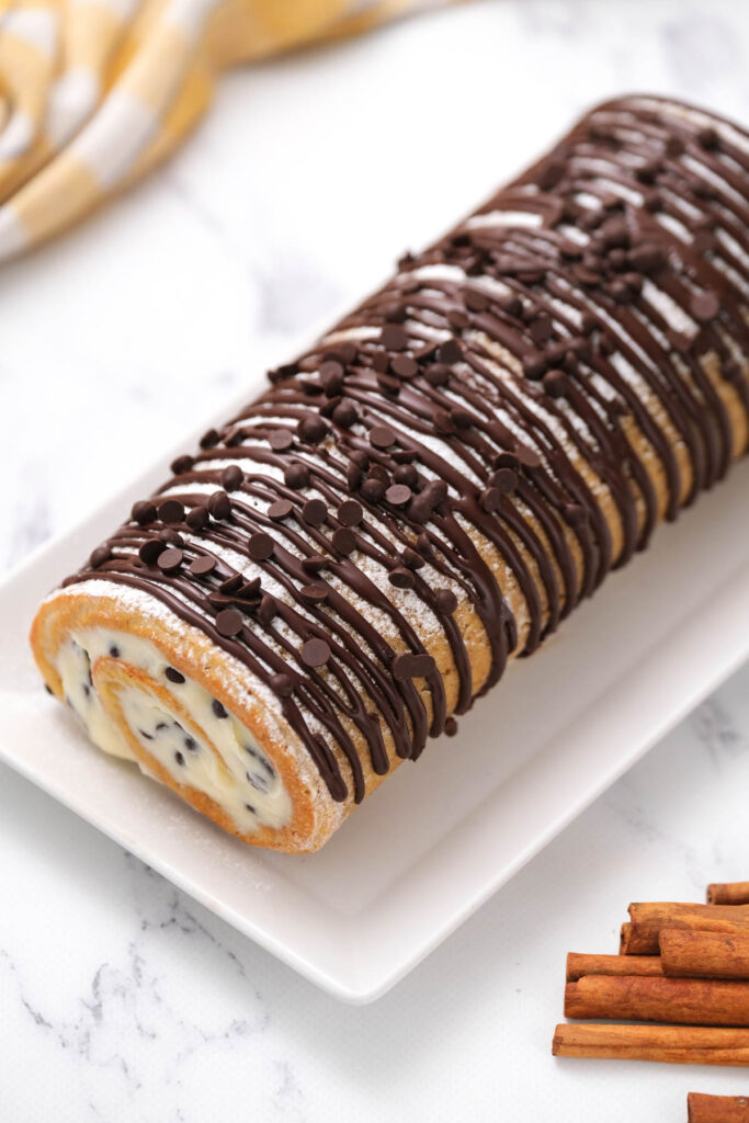 This Chocolate Chip Pumpkin Roll is a fun twist on a classic pumpkin roll! With a fluffy cream cheese filling and mini chocolate chips! overhead view of Chocolate Chip Pumpkin Roll on white plate.